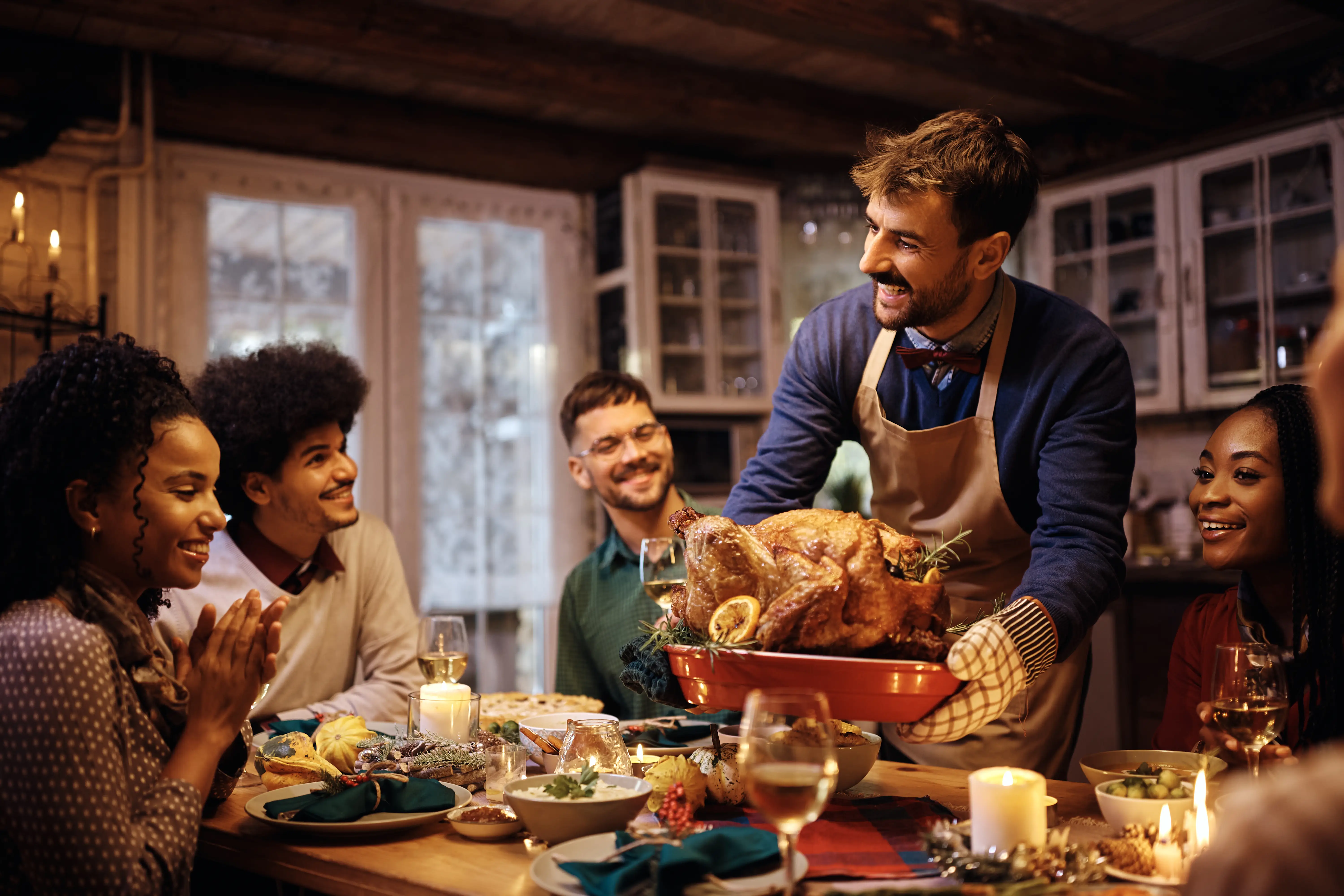 a man holding a turkey in a room with other people