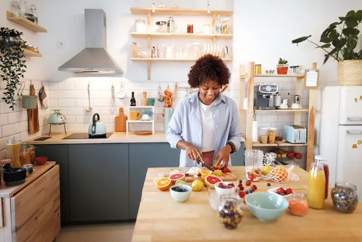 a woman cutting fruit in a kitchen