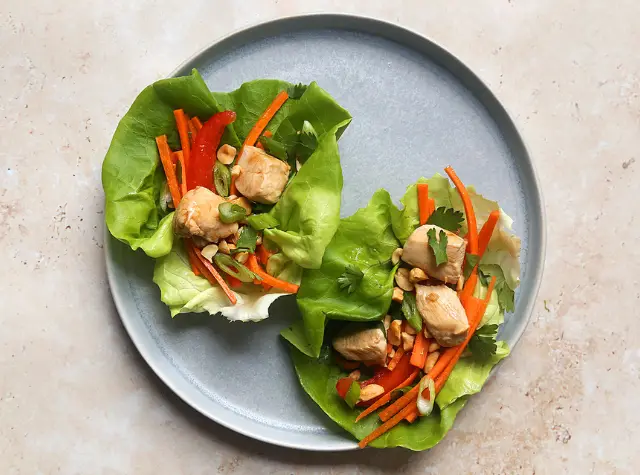 a plate of lettuce wraps with meat and vegetables