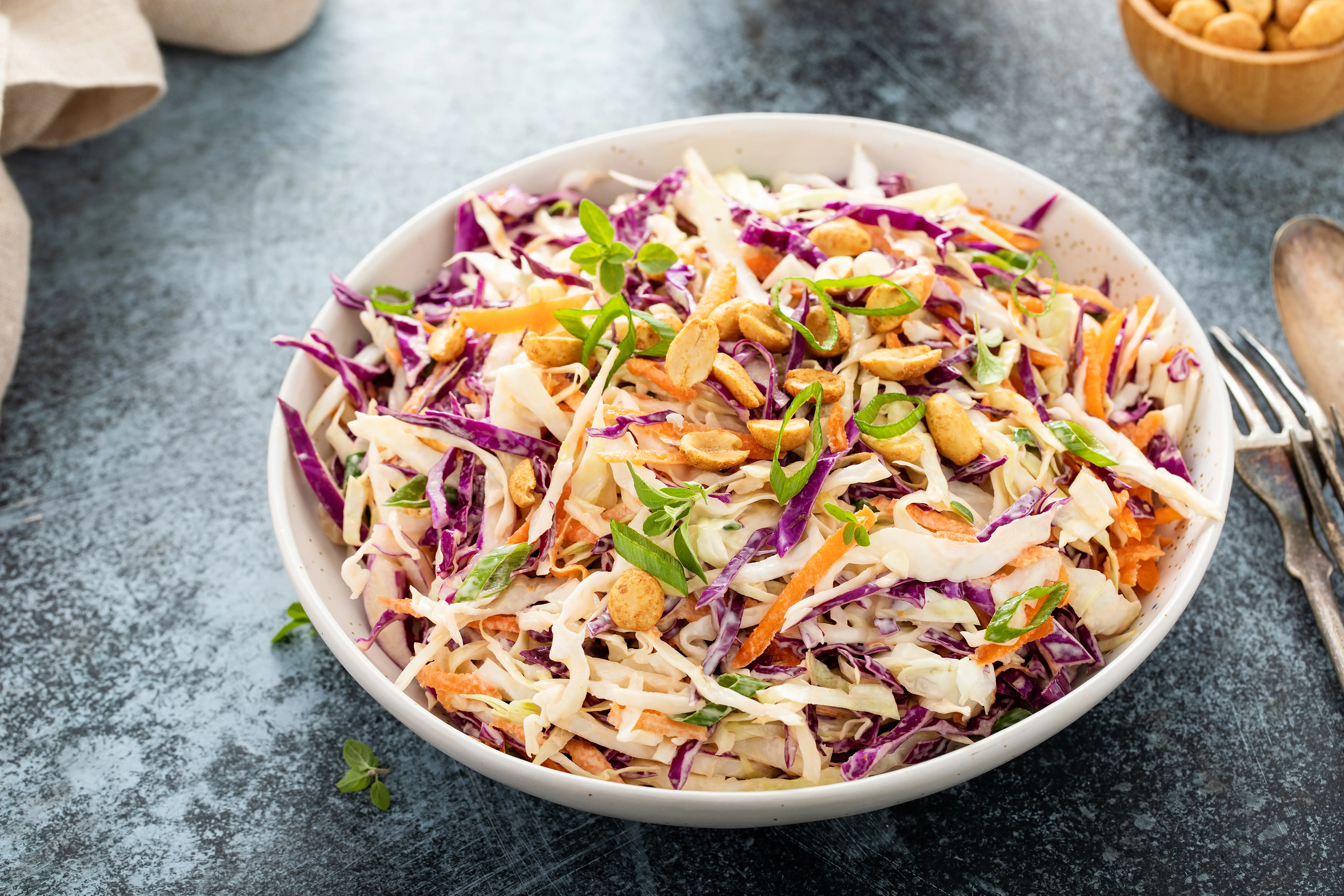 a bowl of coleslaw with peanuts and vegetables