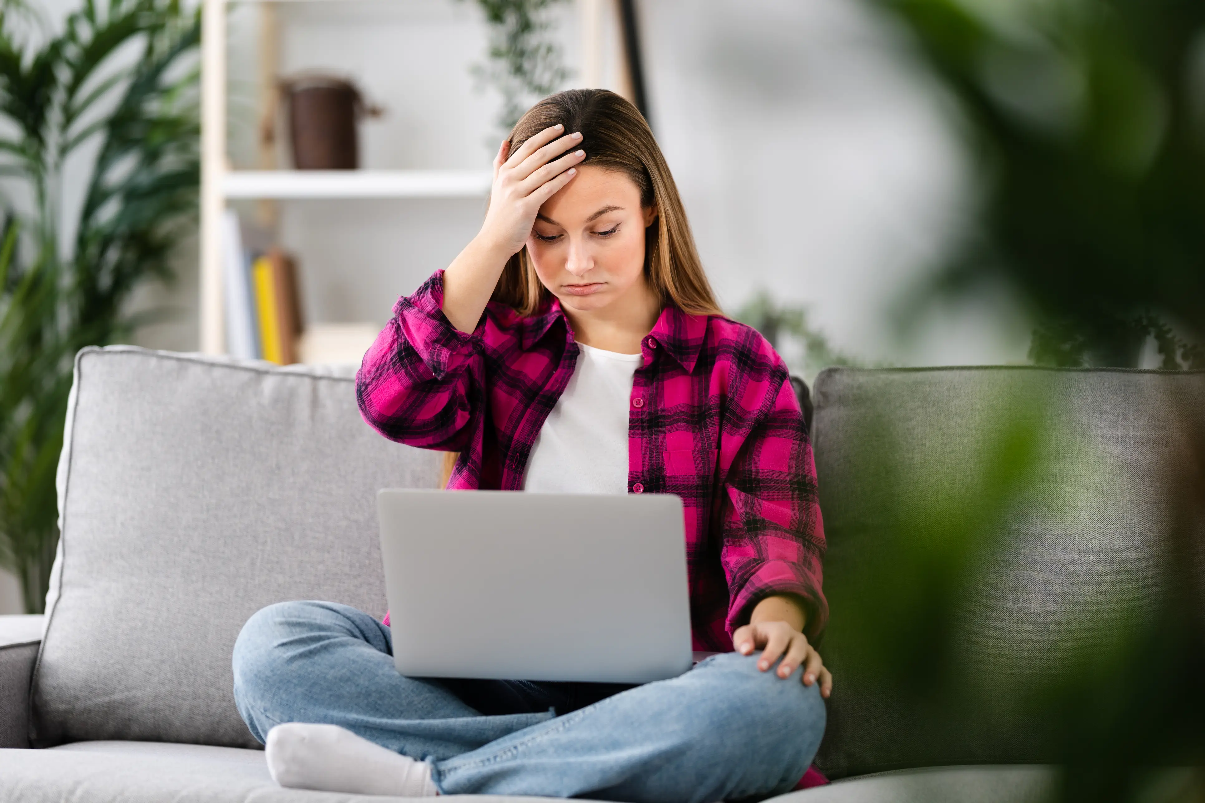 a woman sitting on a couch with her hand on her head
