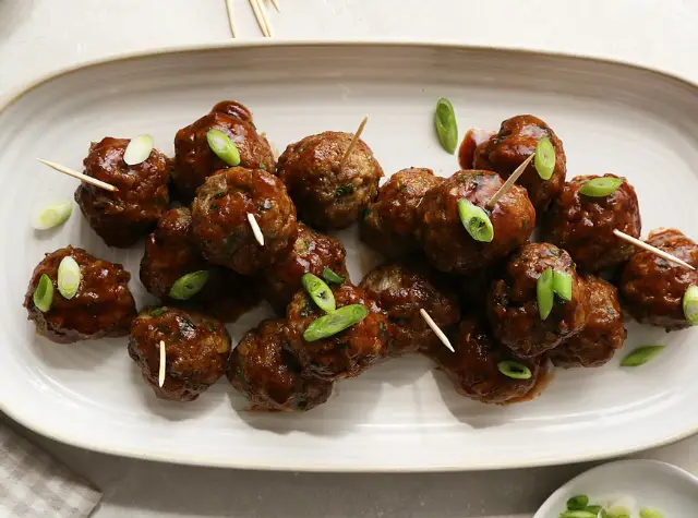 a plate of meatballs with green onions on it